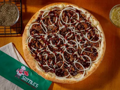 Pizza salgada da Sottile's com cobertura escura de calabresa e cebola