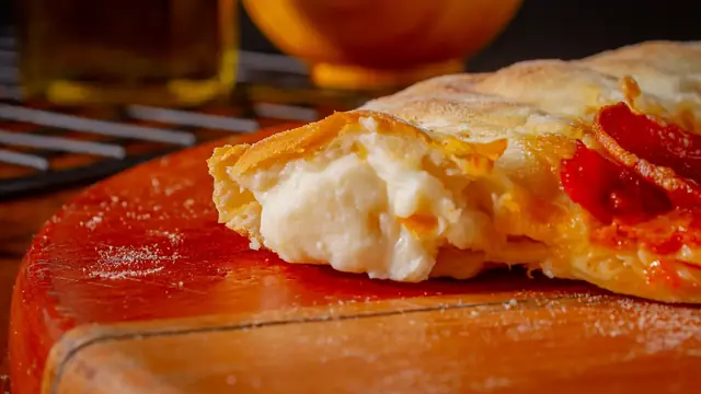 Close da borda de uma pizza da Sottile's, com o queijo derretido escorrendo